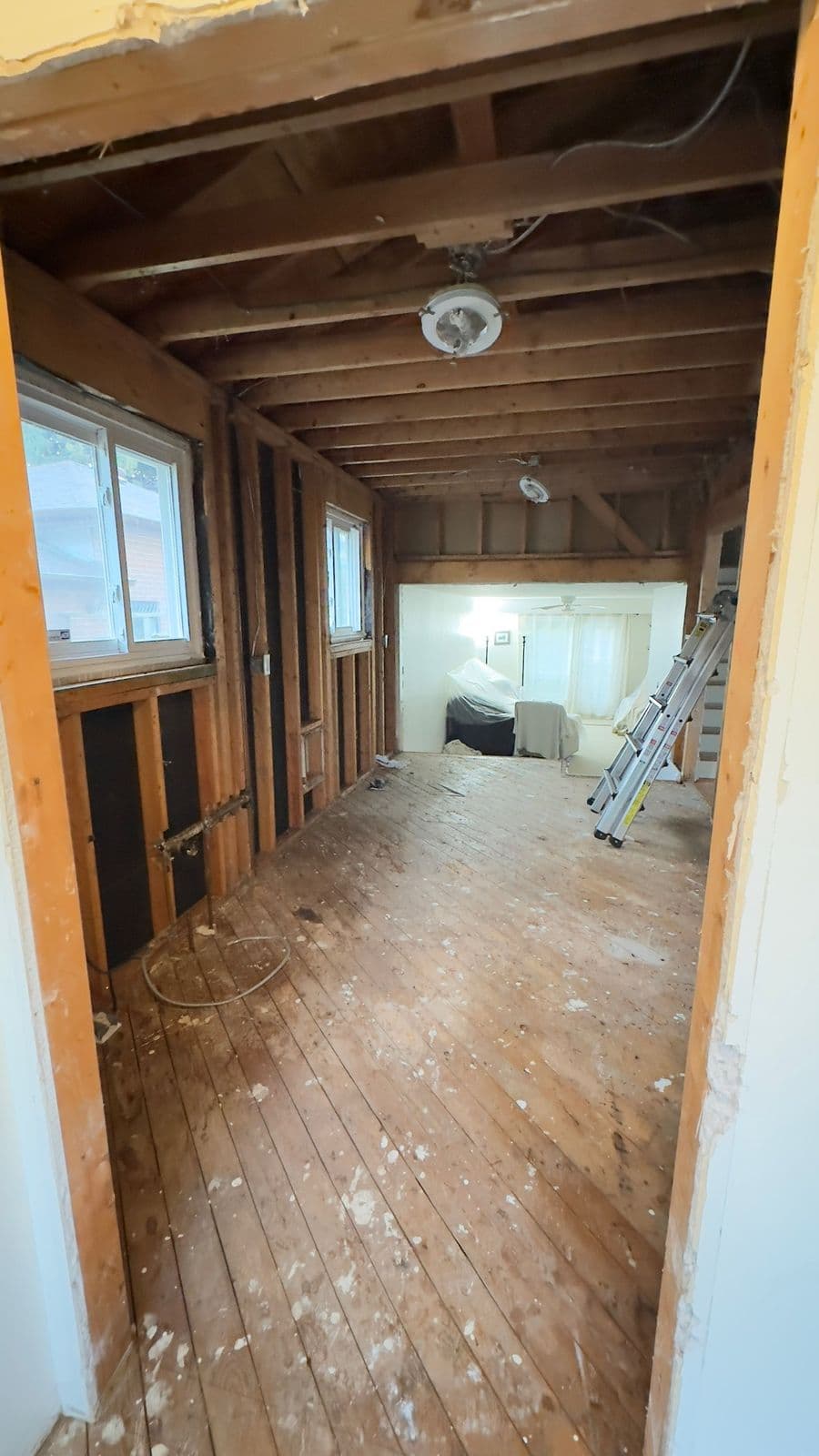 Interior stripped to clean framing after finished abatement, daylight through windows